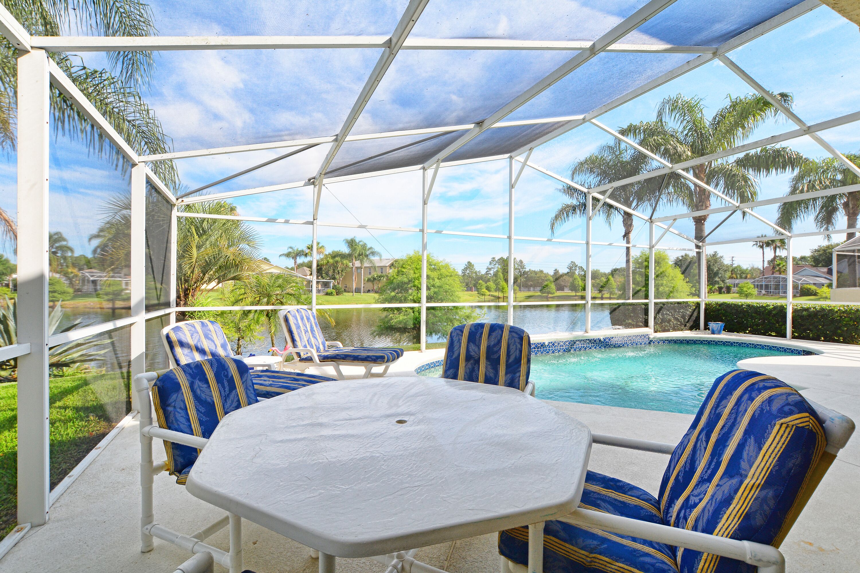 A covered outdoor area with a pool, lounge chairs, and a table.