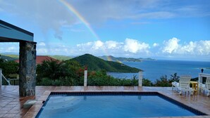 A swimming pool with a view of the ocean and a rainbow. - Mesmerizing view with pool 2 bedroom stone cottage in Coral Bay (St John)