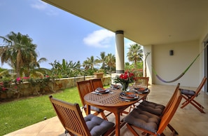 An outdoor patio with a round table, chairs, and a hammock. - Amazing 2B apartment in Alegranza Luxury Condo, San José del Cabo. (Campo de Golf Fonatur)