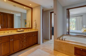 A modern bathroom with a double sink vanity, a large mirror, a bathtub, and a view of the outdoors. - Amazing 2B apartment in Alegranza Luxury Condo, San José del Cabo. (Campo de Golf Fonatur)