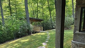 A stone pathway leading to a wooden structure surrounded by lush greenery.