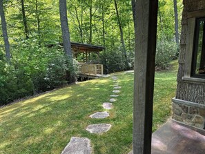 Un sendero de piedra que conduce a una estructura de madera rodeada de exuberante vegetación.