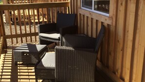 Une terrasse en bois avec des meubles en osier et une porte vitrée.