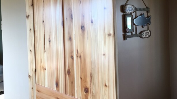 Une porte de grange coulissante en bois avec des ferrures métalliques, un panneau mural représentant un poisson et un interrupteur.