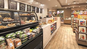 Un comptoir de boulangerie où sont exposées des pâtisseries, ainsi qu’un rayon de produits de charcuterie avec des viandes et des salades emballées.
