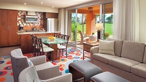 Une cuisine moderne avec une table à manger en verre, un canapé et une vue sur un terrain de golf.