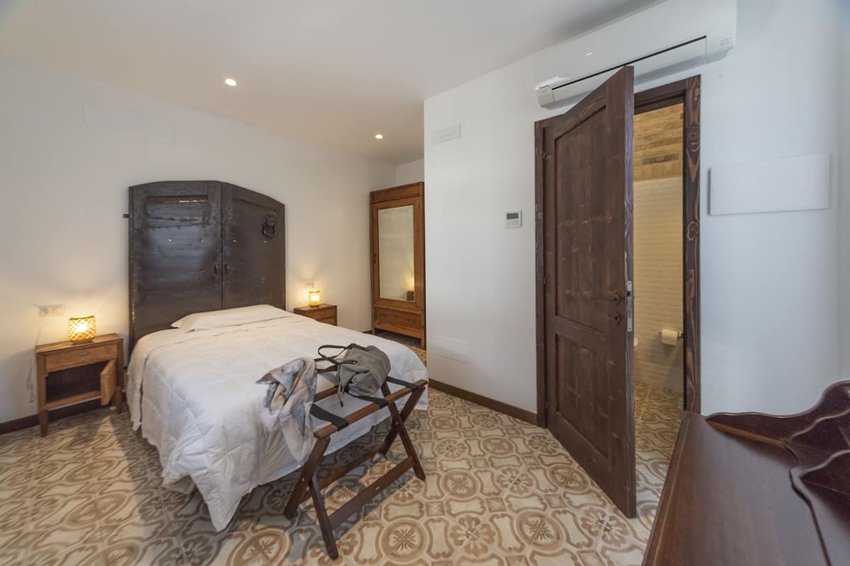 Ein Schlafzimmer mit Bett, Nachttischen, einem Kleiderschrank und einer Tür zum Badezimmer.
