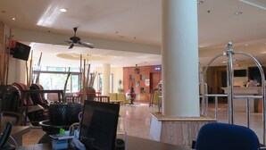 Eine geräumige Lobby mit einer Rezeption, einer Sitzecke und einer großen Säule.