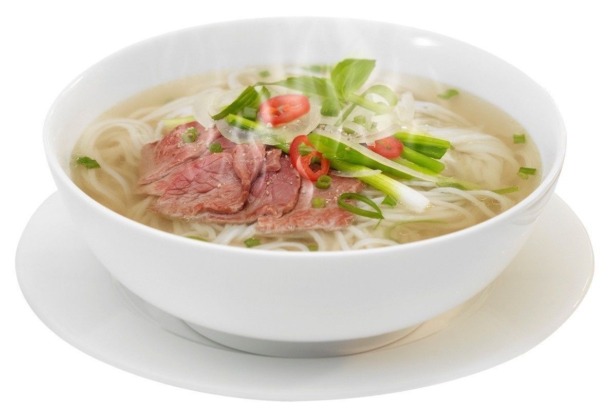 A bowl of noodle soup with beef slices, green onions, and red chili slices.