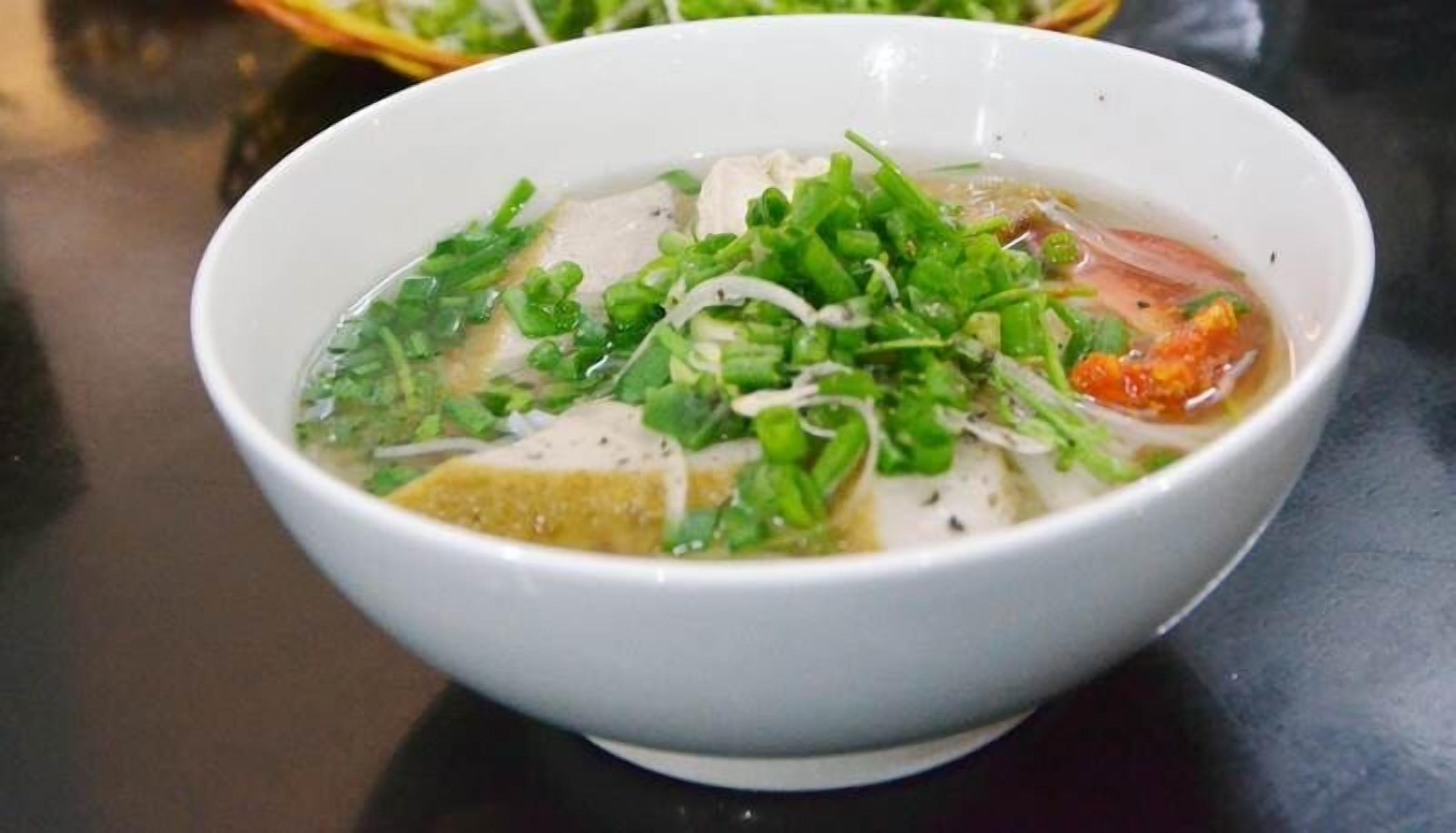 Eine Schüssel Suppe mit grünen Toppings und klarer Brühe.