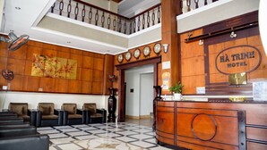 A lobby with a reception desk, multiple seating areas, and a staircase.