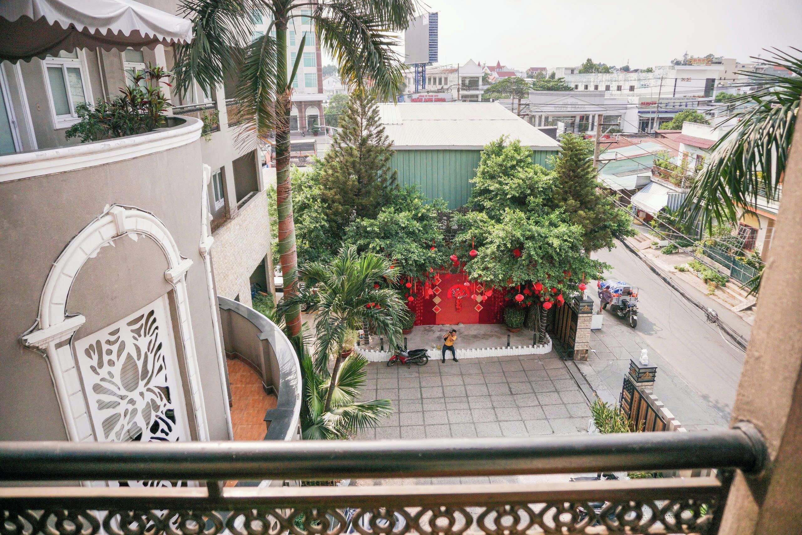 A balcony with a view of a street, a building with a green facade, and a red decoration.