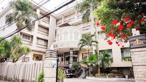 A hotel with a central courtyard, a staircase leading to the entrance, and a vehicle parked outside.