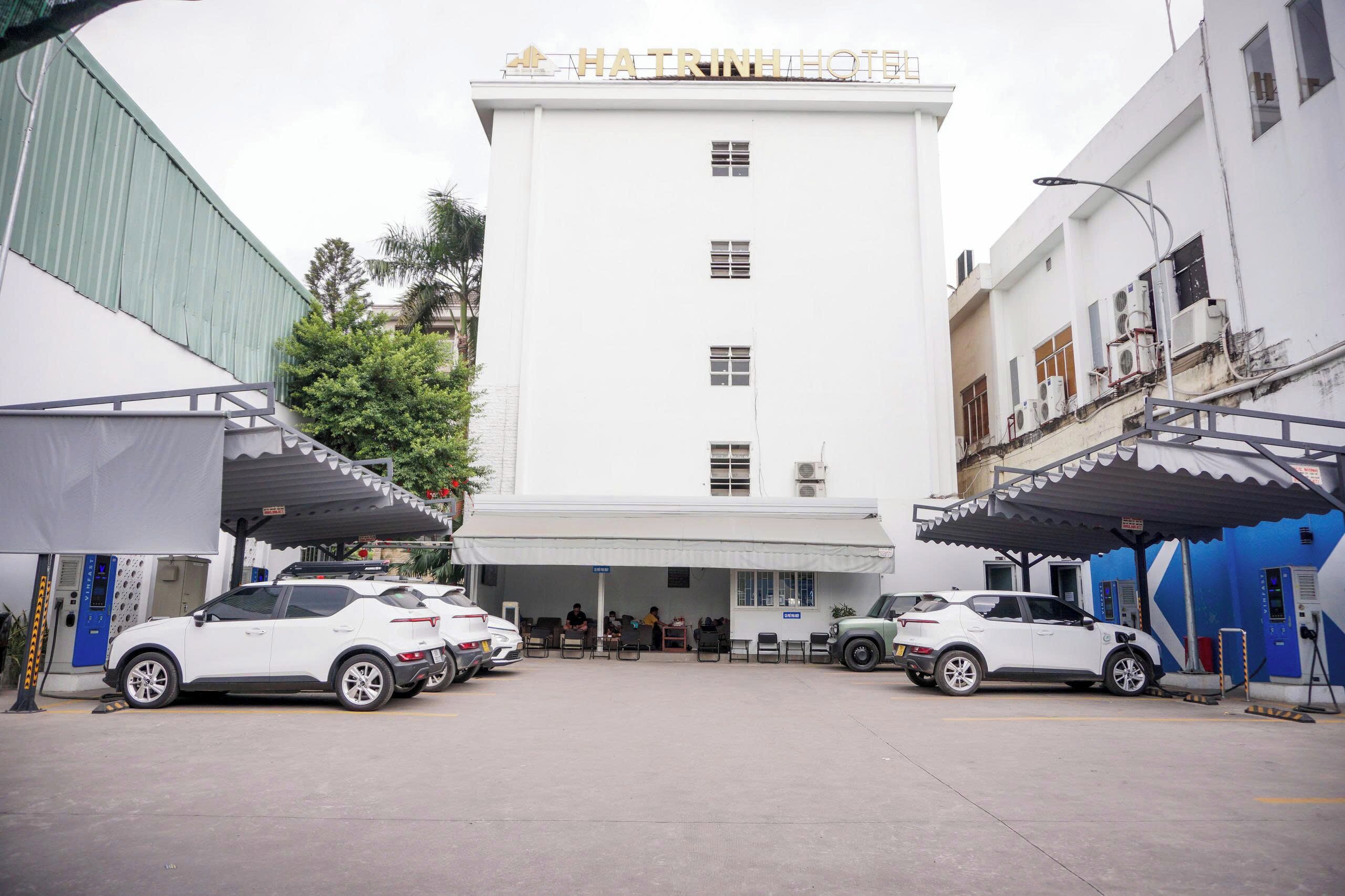 A hotel with a white facade, multiple parked cars, and a covered entrance area.
