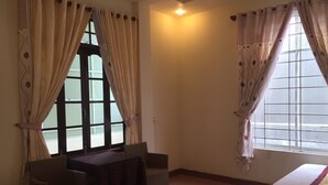 A room with a bed, a chair, a table, and two windows with curtains. - Dang Tuan Hotel (Hue)