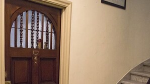 Una porta d'ingresso in legno con una targa, una scala con corrimano e un quadro incorniciato al muro.