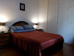 A bedroom with a bed, two bedside tables, a nightstand, a framed picture on the wall, and a wardrobe. - Mundo Vita (Buenos Aires)