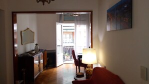 Corridoio che conduce a un balcone con vista sull'esterno. Una lampada si trova a destra e una sedia al centro.