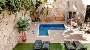 A rooftop pool area with lounge chairs, a small table, and string lights. - Astuto Boutique Jerez - Adults Only (Jerez de la Frontera)