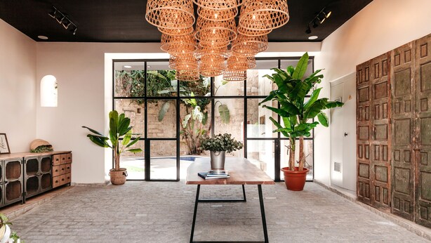A spacious room with a large window, a wooden table with a metal frame, and a hanging wicker chandelier. - Astuto Boutique Jerez - Adults Only (Jerez de la Frontera)