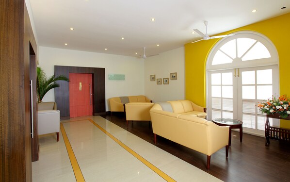 Un lobby moderno con una pared de acento amarilla, una puerta roja y dos sillones amarillos.