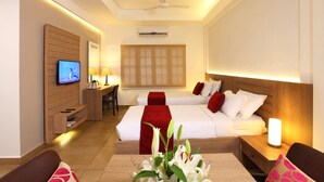 A hotel room with two beds, a TV, a desk, and a coffee machine. - Hotel Luciyapalace (Thrissur)