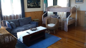 A room with a bunk bed, a sofa, a wicker chair, a coffee table, and a painting on the wall. - Independent holiday unit (Bicheno)