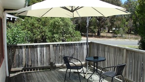 A wooden deck with a table and two chairs under a large umbrella. - Independent holiday unit (Bicheno)