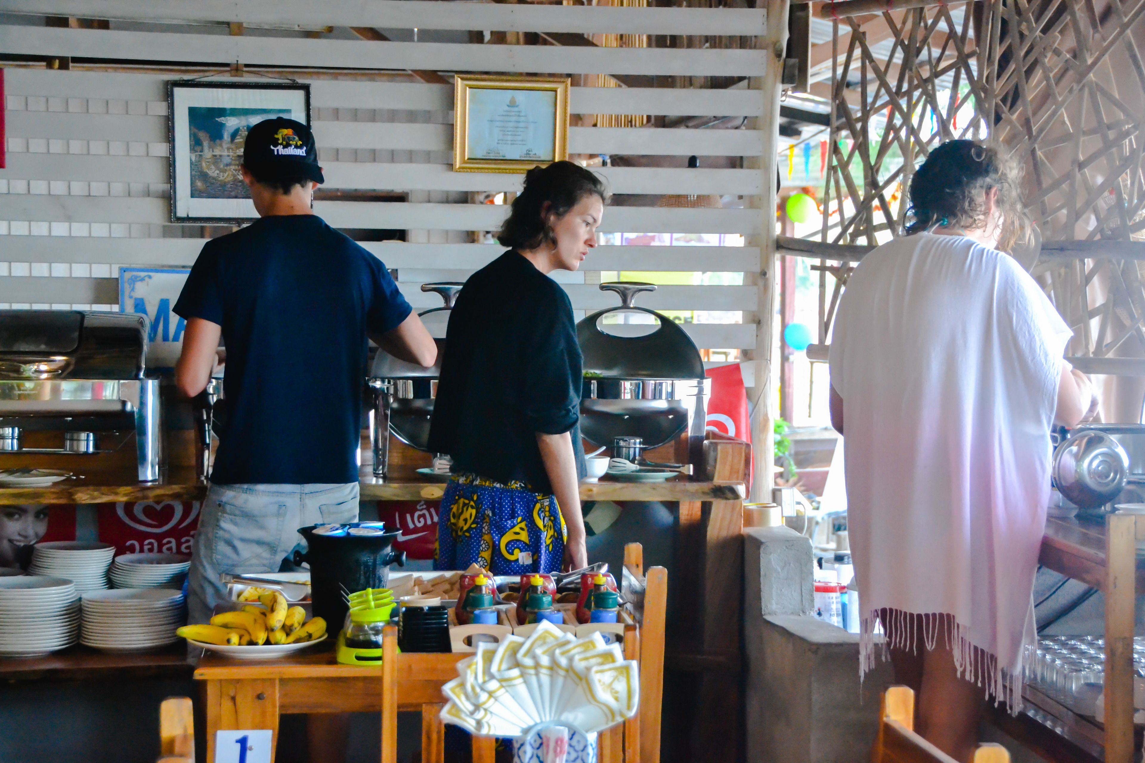 A restaurant with a wooden counter, a grill, and a variety of dishes and condiments on display.