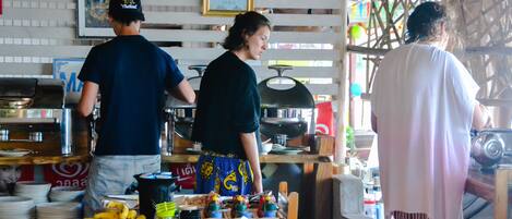 A restaurant with a wooden counter, a grill, and a variety of dishes and condiments on display.