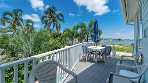 A deck with outdoor furniture, a railing, and a view of the water. - Sea la Vie offers Bay Views, Pool, and is Pet Friendly (Fort Myers Beach)