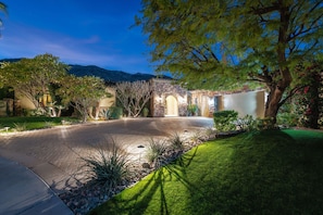 Surrounded by lush greenery, this property features a stone facade and arched doorway, blending traditional and modern design elements.