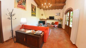 Un salon chaleureux avec un plafond en bois, une cheminée, un téléviseur et un canapé rouge.
