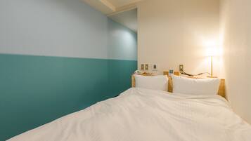 A hotel room with a bed, a nightstand, a lamp, and a wall with a teal and white color scheme.