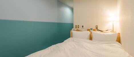 A hotel room with a bed, a nightstand, a lamp, and a wall with a teal and white color scheme.