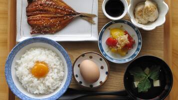 Una bandeja con un plato de pescado a la parrilla, un bol de arroz con huevo, un bol de verduras encurtidas, un recipiente pequeño de caviar y dos tazas pequeñas de salsa de soja.