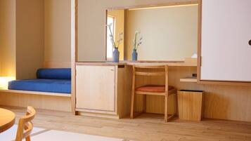 A compact room with a wooden desk, a blue cushioned bench, and a small chair.