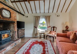 Cozy living room with a fireplace, sofa, dining area, and large window.