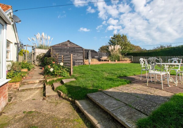 Enjoy outdoor dining and relaxation in this serene backyard with a garden, lawn, and seating area.