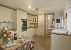 Kitchen with oven, sink, and central island, featuring a wooden table and chair.