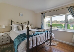 Classic bedroom with a four-poster bed, large window, and wooden floor.