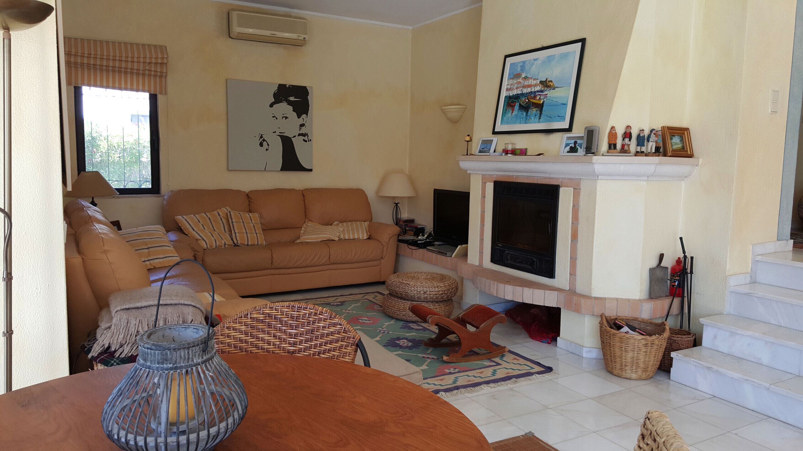 Un salon avec un canapé, une cheminée, un téléviseur et un tableau accroché au mur.