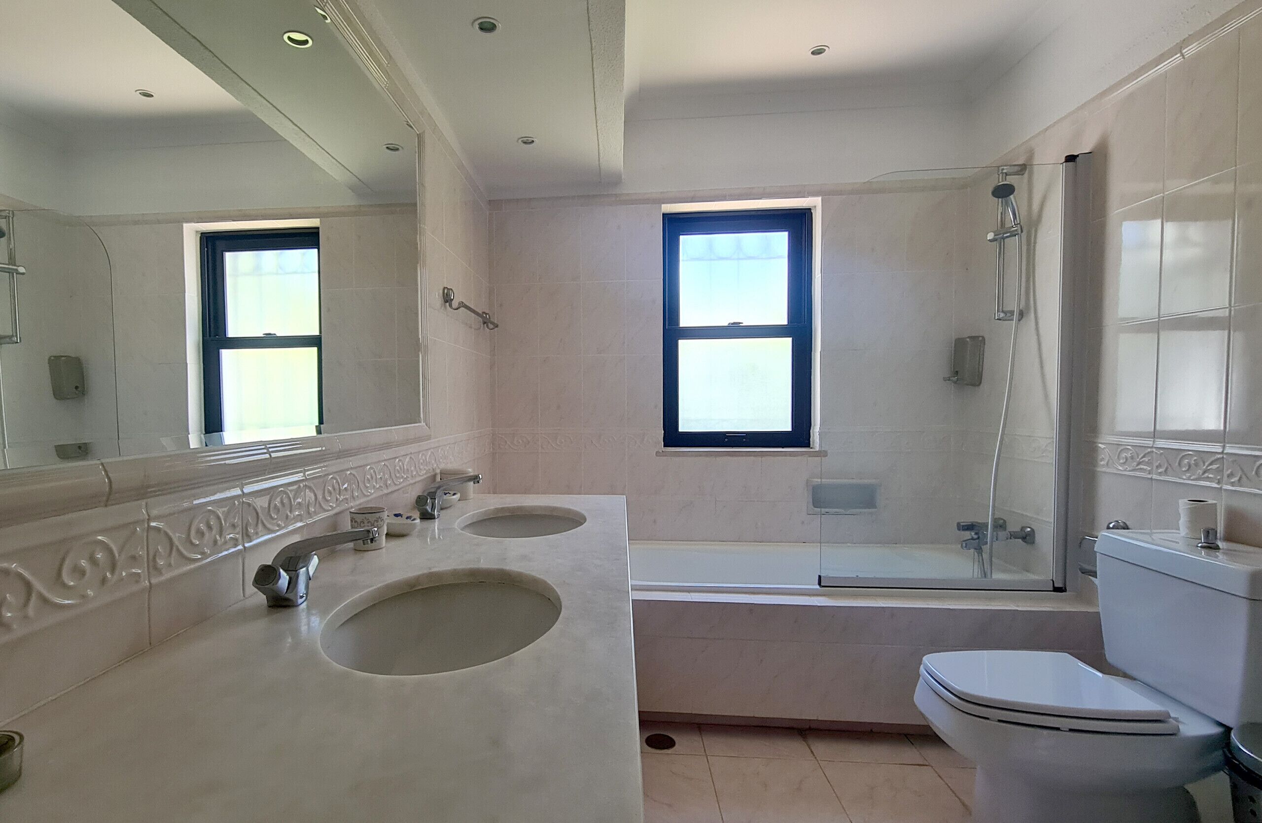 A bathroom with two sinks, a toilet, and a bathtub with a glass shower enclosure.