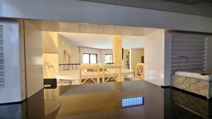 A spacious living area with a dining table and chairs, a sofa, and a view of a balcony. - Dunas Douradas Beach Villa (Vale do Lobo)