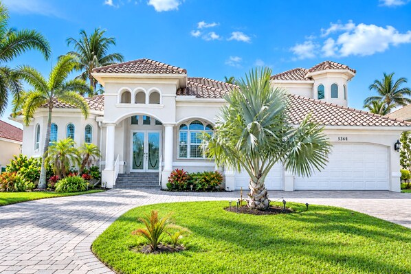A two-story house with a white facade, a tiled roof, and a garage.
