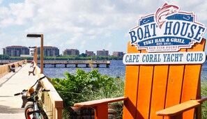 A waterfront sign for Boat House, a tiki bar and grill, and Cape Coral Yacht Club.