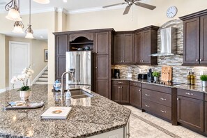 A modern kitchen with dark wood cabinets, stainless steel appliances, and a granite countertop.