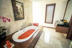 A bathroom with a large bathtub, a sink, and a vanity with a mirror. - Villa Pasraman Baghawan (Jimbaran)