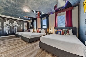 A hotel room with three beds, Star Wars themed wall art, and a Star Wars themed pillow.