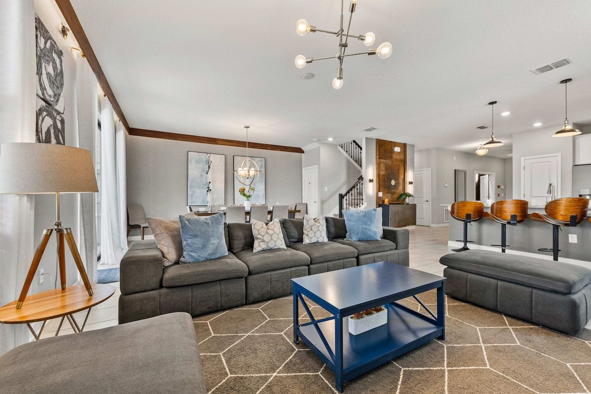 A modern living room with a sectional sofa, a coffee table, and a dining area with chairs.